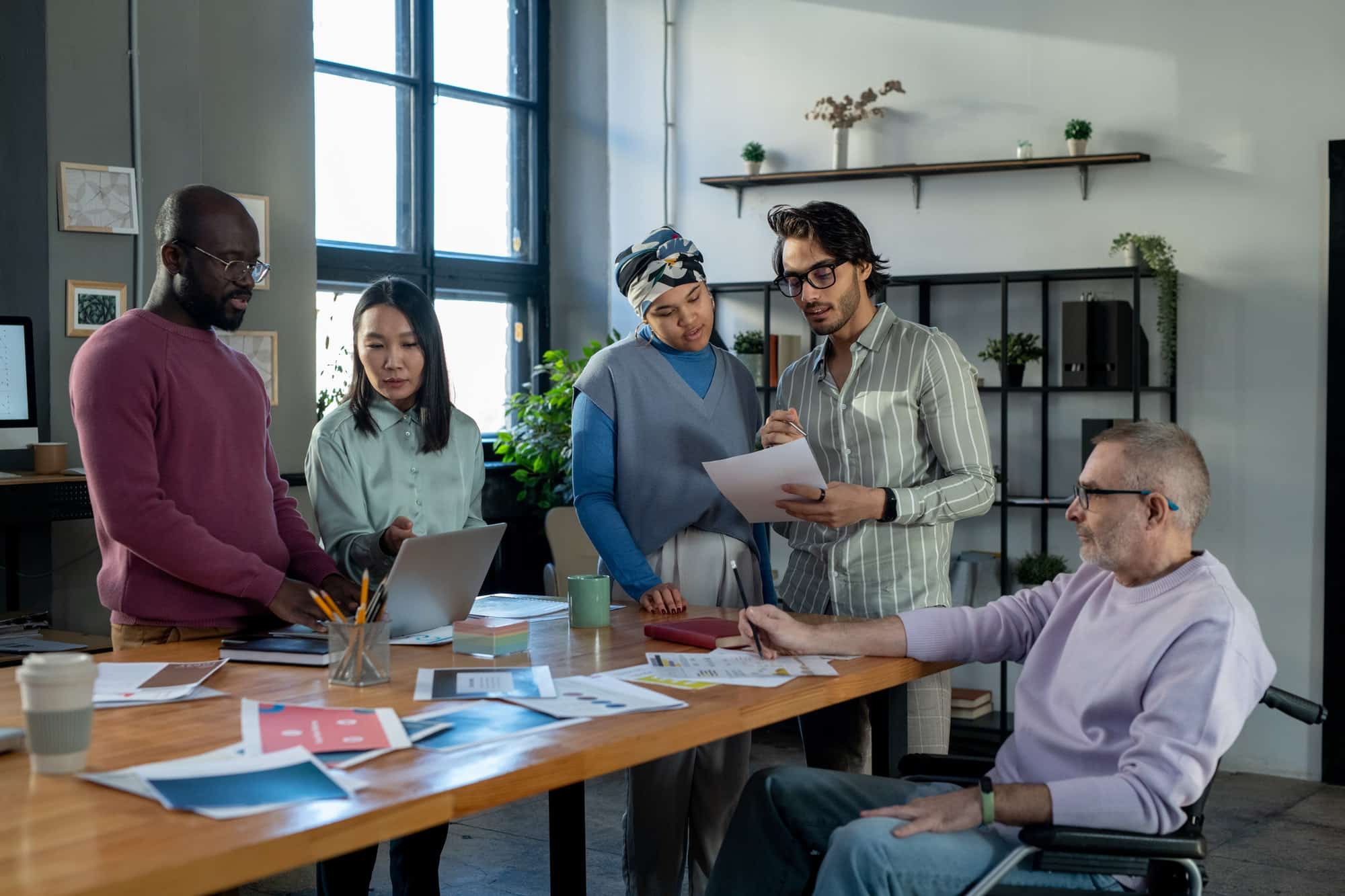 Mitarbeiter im Unternehmen stehen am Tisch.Datenschutz im Unternehmen Sichern Sie Ihr Unternehmen mit Expertise – Zertifizierte Datenschützer stehen Ihnen zur Seite!